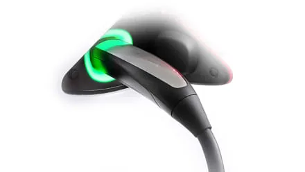 Close-up of a Tesla NACS charge port handle glowing green.